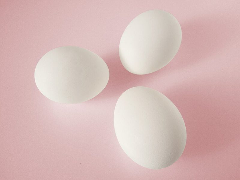 Three white eggs on a pink background