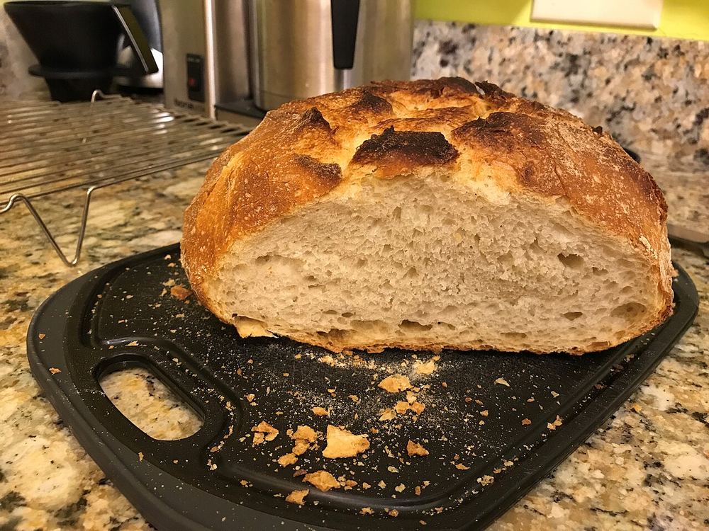 A sliced loaf of sourdough bread showing an open, airy crumb