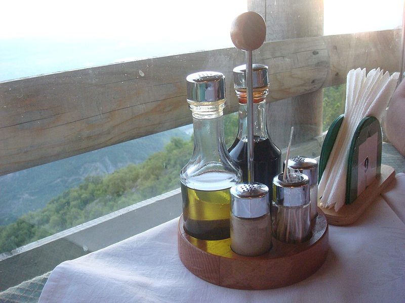 Oil and vinegar bottles on a wooden tray at a restaurant table