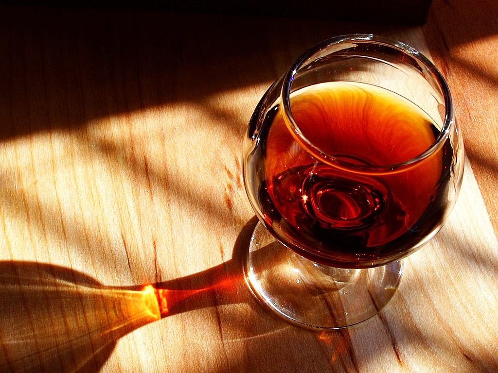A glass of port wine on a wooden table in warm sunlight